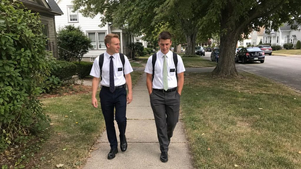 Two young Latter-day Saint missionaries walking together through a residential neighborhood