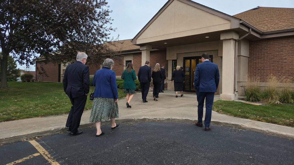 People arriving at a Latter-day Saint meetinghouse for a funeral service