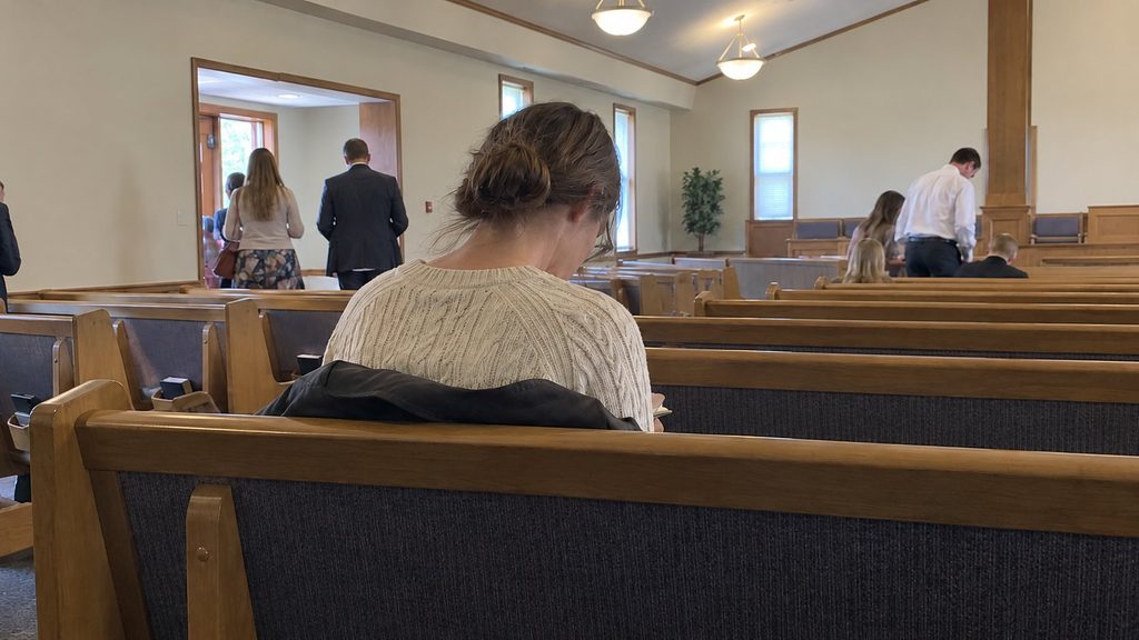 A Latter-day Saint member sitting quietly in a chapel before or after Sunday worship