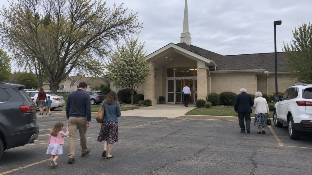 Latter-day Saint families and individuals arriving at a meetinghouse for Sunday worship