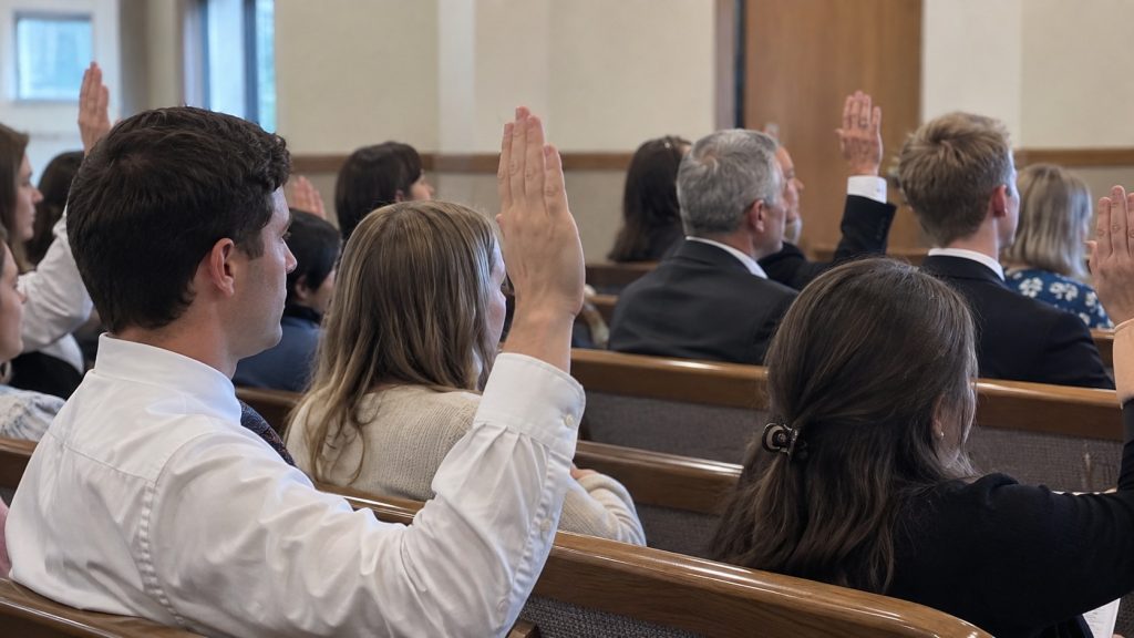 Latter-day Saints raising their hands to sustain someone in a Church calling
