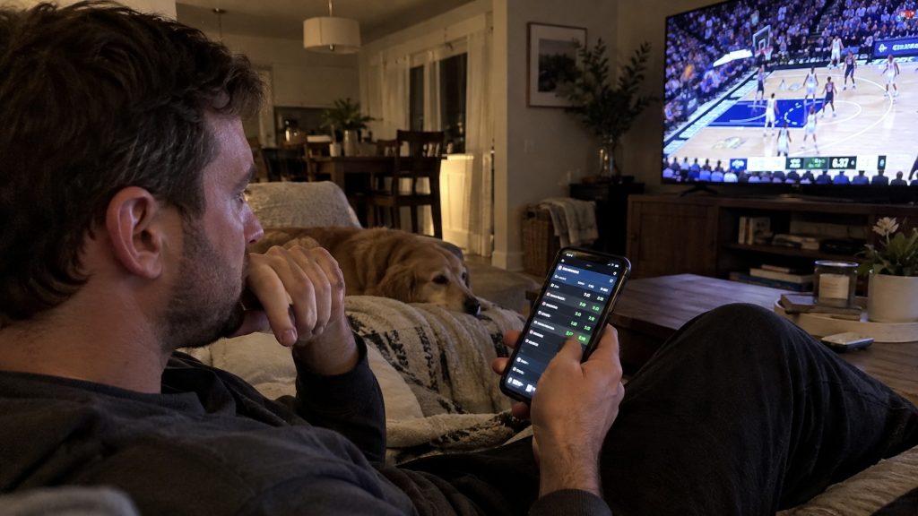 Sports betting on a smartphone while watching a basketball game