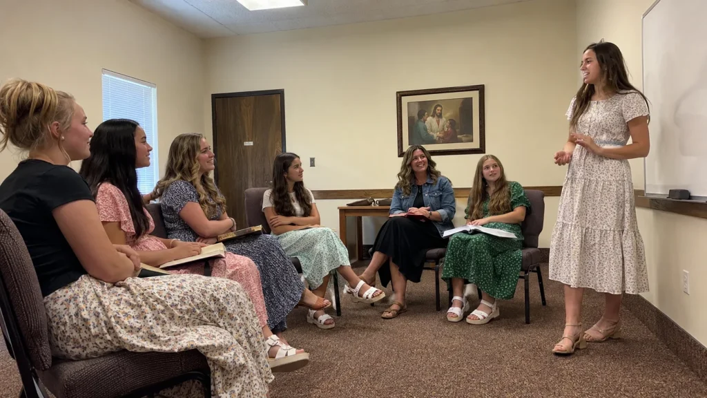 Young Women participating in a Sunday class discussion with their leader in a Latter-day Saint meetinghouse