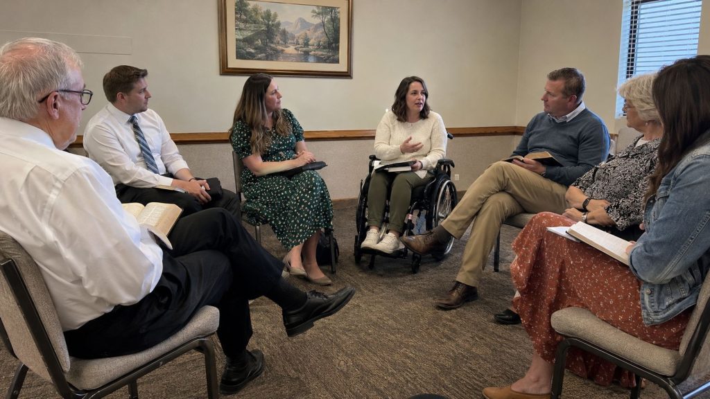 A Latter-day Saint woman using a wheelchair participating in a Sunday School discussion with other Church members.